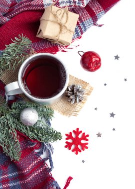 Sıcak noel içeceği kupada siyah çay, koni, hediye, gümüş top, elma, köknar ağacı, beyaz arka planda ekose. Kış zamanı en iyi görünüm.