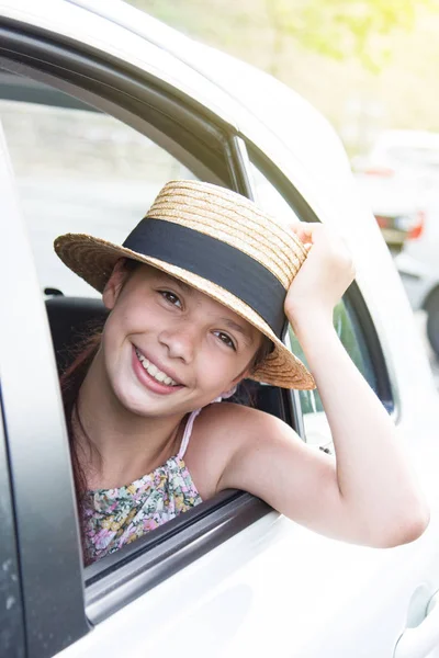 Smiling happy girl in straw hat in car window. Travel with kids. Travel by car — Stock Photo, Image