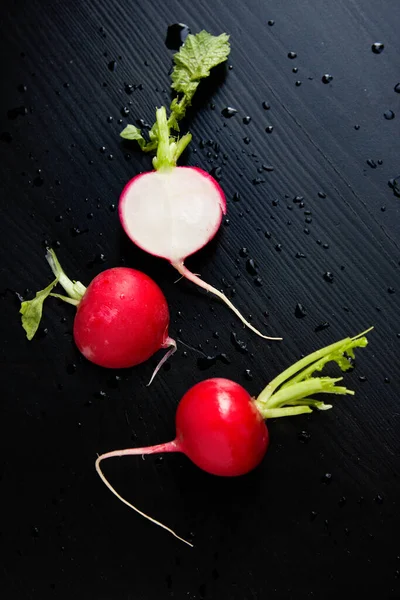 Radish on black with water drops