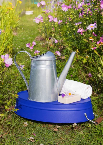 金属浇水罐 紫色水盆 马桶肥皂和白色毛巾 花园里有鲜花 洗浴工具 夏天在村子里 — 图库照片