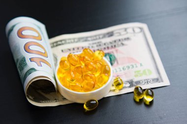 Siyah arka planda balık yağı ve dolar kapsülleri. Pahalı bir ilaç. İlaç kıtlığı. Pandemik. Coronavirüs