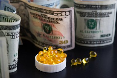 Siyah arka planda balık yağı ve dolar kapsülleri. Pahalı bir ilaç. İlaç kıtlığı. Pandemik. Coronavirüs