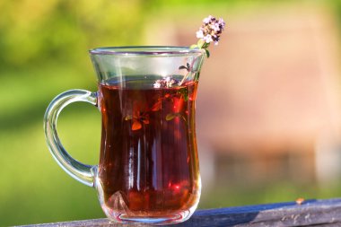 Yazın kekik otlarının içinde bir fincan sıcak bitkisel çay. Güneşli bir günde Türk fincanı