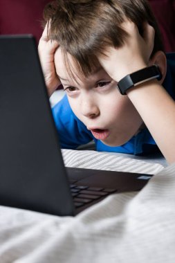 Bilgisayardan öğrenme konusunda şaşkın ve şaşırmış bir çocuk. Şok içeriği. İyi ya da kötü. Karantinaya alın. Evde online ders, sosyal mesafe, Çevrimiçi eğitim kavramı, evde eğitim.