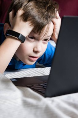 Bilgisayardan öğrenme konusunda şaşkın ve şaşırmış bir çocuk. Şok içeriği. İyi ya da kötü. Karantinaya alın. Evde online ders, sosyal mesafe, Çevrimiçi eğitim kavramı, evde eğitim.