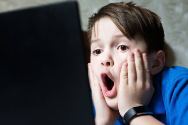 Bilgisayardan öğrenme konusunda şaşkın ve şaşırmış bir çocuk. Şok içeriği. İyi ya da kötü. Karantinaya alın. Evde online ders, sosyal mesafe, Çevrimiçi eğitim kavramı, evde eğitim.