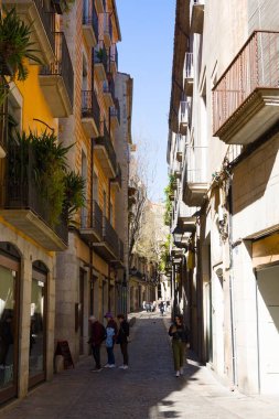 Girona, İspanya - 24 Şubat 2020: Girona 'daki eski bir medivedial kasabada turistler dar bir sokakta yürüyor