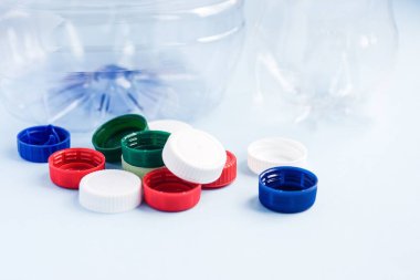 Şişelere karşı renkli plastik kapaklar. Mavi arka planda plastik ambalaj çöpü. Plastik ile çevre kirliliği kavramı.