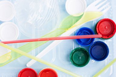 Su şişeleri, pipet, tabak, çatal, bıçak ve şişe kapağı da dahil olmak üzere tek kullanımlık plastik çöp yığını. Plastik ile çevre kirliliği kavramı