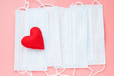 Pembe arka planda kırmızı kalpli mavi kumaş maskeler. Cesur yürek ve tüm tıp işçilerine minnettarlık. Coronavirus, COVID-19, karantina sırasında salgın. Hemşire günü