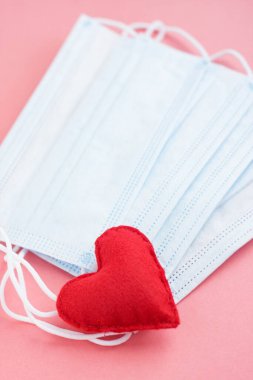 Pembe arka planda kırmızı kalpli mavi kumaş maskeler. Cesur yürek ve tüm tıp işçilerine minnettarlık. Coronavirus, COVID-19, karantina sırasında salgın. Hemşire günü