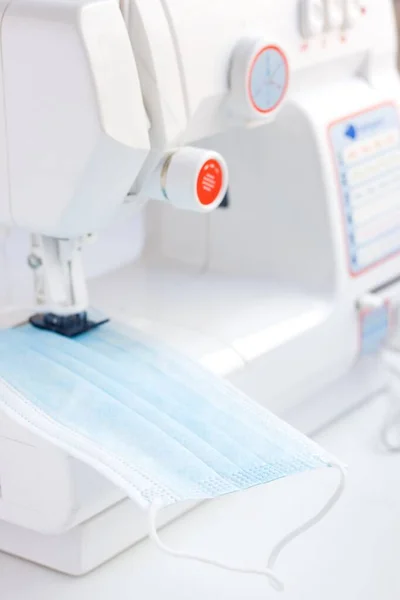 Sewing machine to make mask face fabric. Health care, and coronavirus protect with sew mask. Sewing medical masks to protect against coronavirus.Production of masks on sewing machine during quarantine