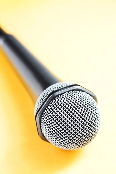 Silver modern microphone with cable on yellow background. Close up. Speaker concept