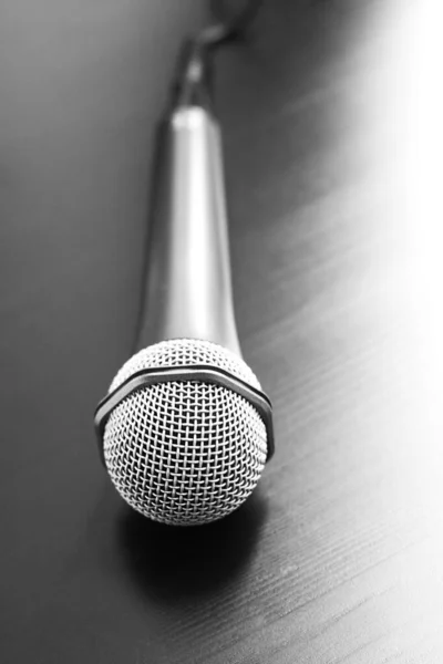 Silver modern microphone with cable on black background. Close up. Speaker concept
