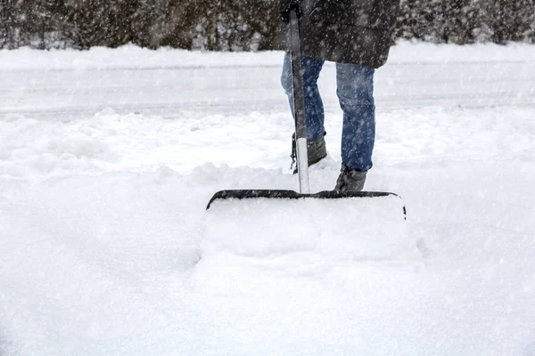 Frau schaufelt Schnee auf Gehweg — Stockfoto