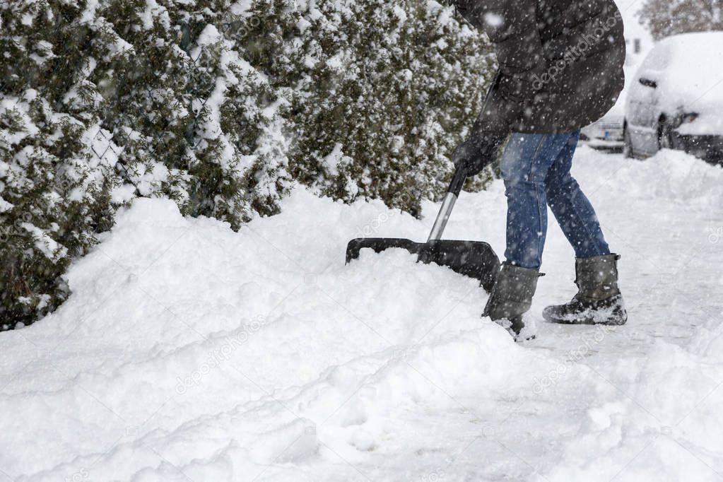Woman shoveling snow on pavement