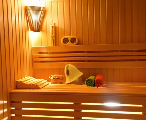 Sauna. Accesorios de baño: cubo, cuchara tallada, sombrero, enrollado en una toalla de rollo y un jarrón de velas perfumadas . — Foto de Stock