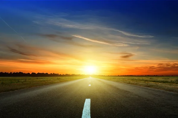 Estrada de asfalto entre os campos ao pôr do sol — Fotografia de Stock