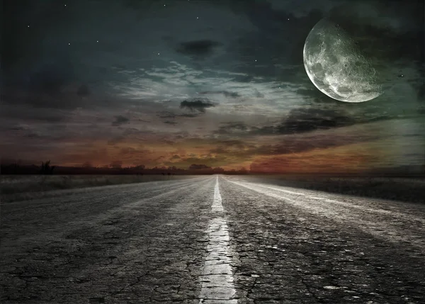 Asphalt road through the fields to a huge moon in the sky — Stock Photo, Image