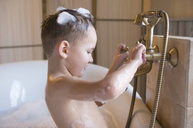 Küçük çocuk küvette banyo yapıyor.,