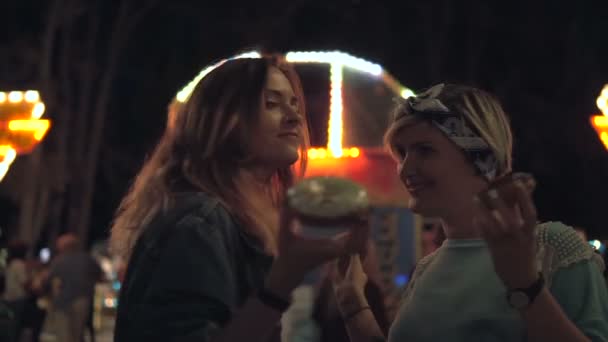 Mejores amigos caminando por el parque. En el fondo las luces del carrusel . — Vídeos de Stock