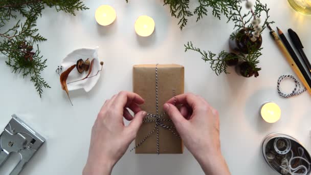Scatola regalo in carta artigianale su sfondo bianco. Presente decorato con parti naturali. Natale o Capodanno, vista dall'alto . — Video Stock