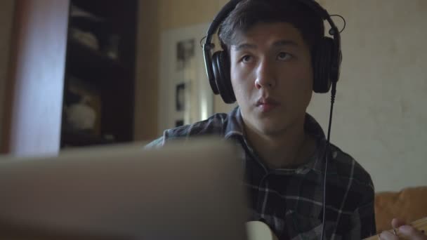 Egy fiatal férfi játszik gitáron, felvétel a zenét otthon — Stock videók