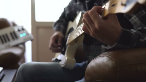 Ein junger Mann spielt Gitarre und nimmt zu Hause Musik auf — Stockvideo