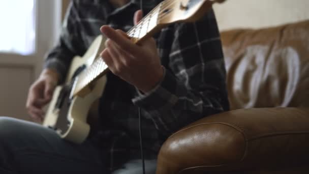 Ein junger Mann spielt Gitarre und nimmt zu Hause Musik auf — Stockvideo