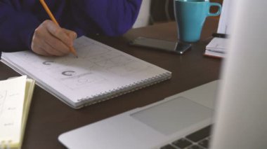 Uygulama geliştirici bir defterde çizimleri çizer. Ev ofis uzaktan eserlerinden