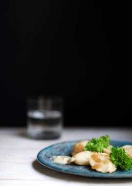 Bir seramik tabak ve salata ile siyah bir arka plan Vareniki 