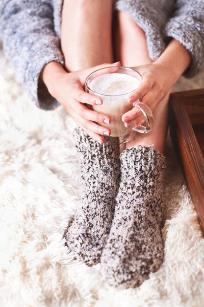 The girl is holding a cup of coffee in a gray coat in knitted so — Stock Photo, Image