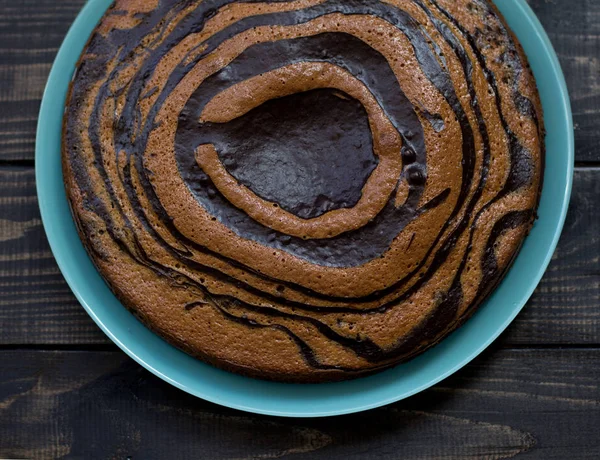 Torta de textura de cebra en un plato azul sobre un fondo de madera. Piso tendido, vista superior —  Fotos de Stock