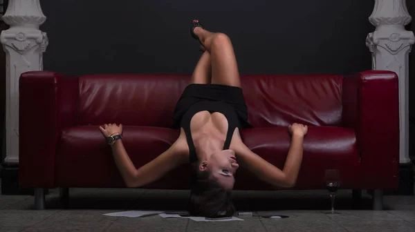 Kırmızı deri koltukta yalan siyah elbiseli güzel genç kadın