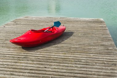 Gölde bir ahşap iskele üzerinde kırmızı bir kayık