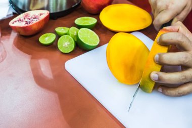 Beyaz tepside meyve doğrayan Latin bir erkek el.