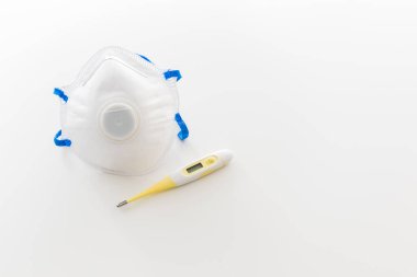 Koronavirüs koruması için bir termometre ve maske, beyaz arkaplanda kopyalanmış alan