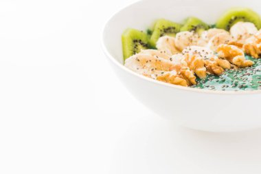 Beyaz arka planda muz, ceviz, kivi ve chia tohumlu spirulina kokteyli kasesi.