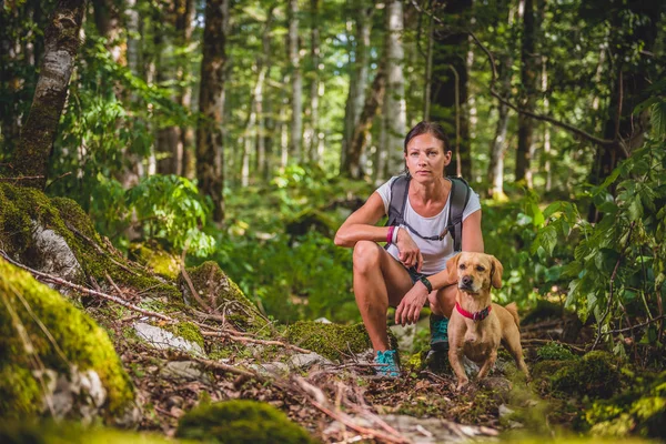 Mulher descansando com cão na floresta — Fotografia de Stock