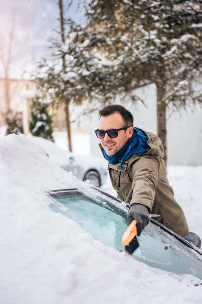 Человек чистки снега покрытый автомобиль — стоковое фото