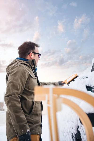 man cleaning snow covered car