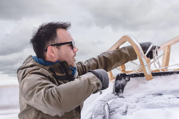 Человек, несущий сани в снегу — стоковое фото