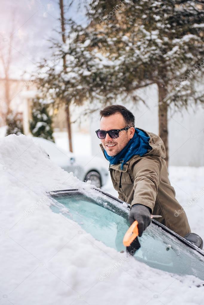 man cleaning snow covered car 