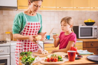 Anne ve kızı pizza hazırlıyor. 