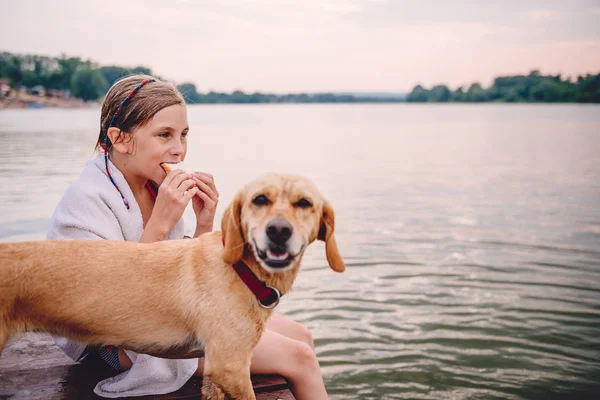Menina Sentada Uma Doca Com Seu Cão Comer Sanduíche Junto — Fotografia de Stock