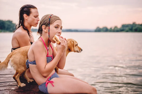 Niña Sentada Junto Río Con Madre Perro Comiendo Sándwich — Foto de Stock