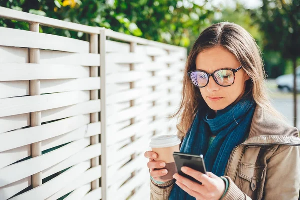 Kahve tutarak ve telefonunuzun ve kadın — Stok fotoğraf