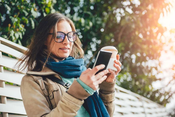 Kahve tutarak ve telefonunuzun ve kadın — Stok fotoğraf