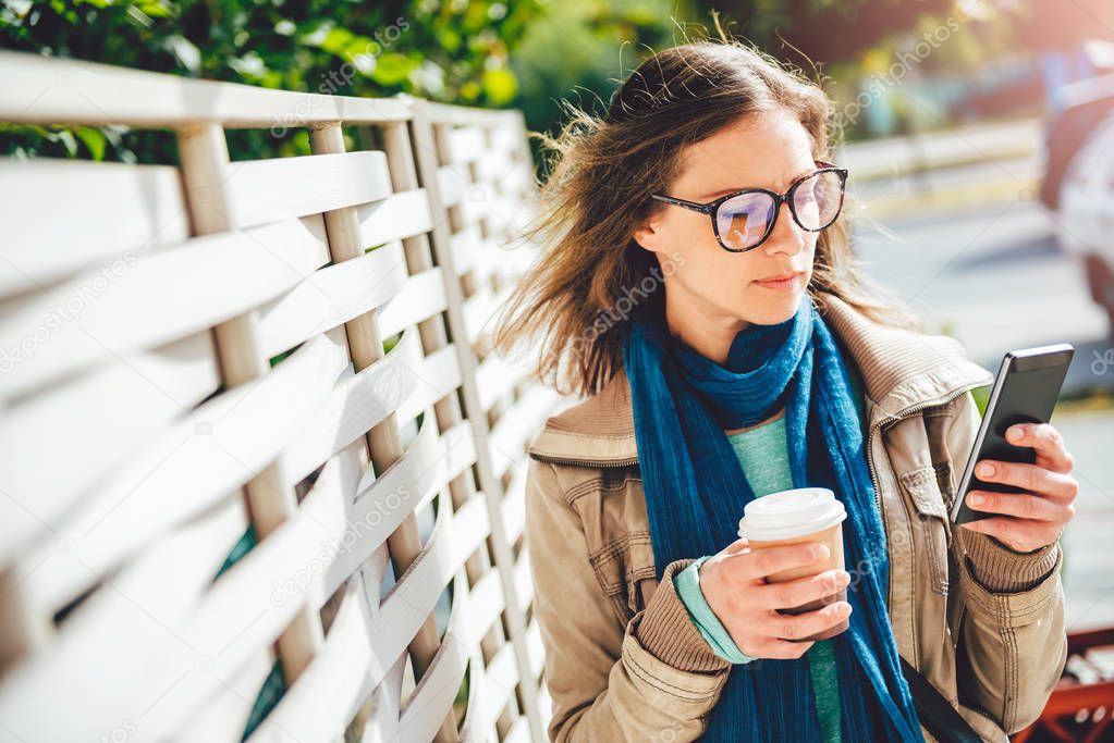 Woman holding coffee and smart phone 