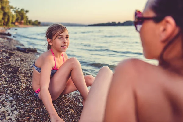 Anne ve kızı gün batımında sahilde